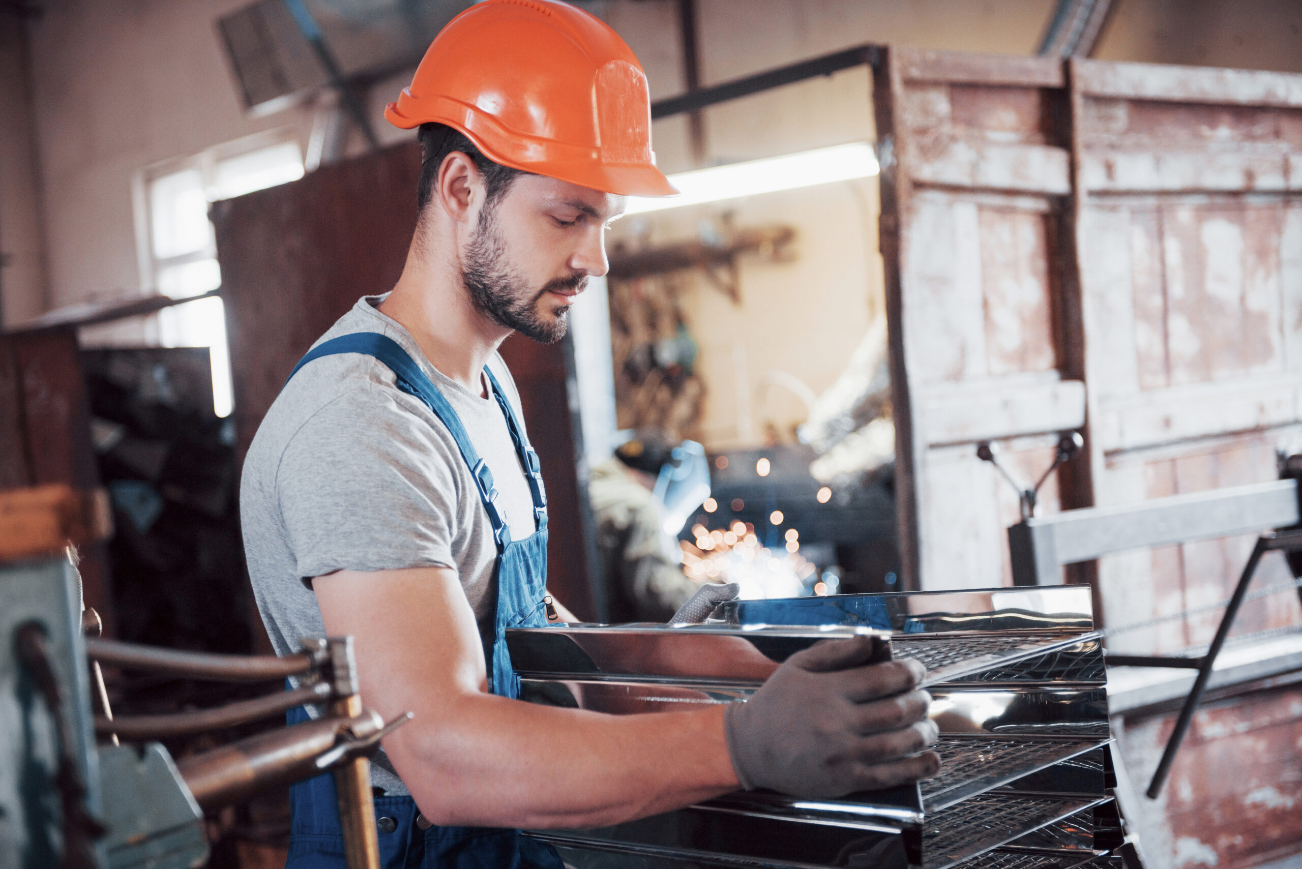 Portrait of a young worker in a hard hat at a large waste recycling factory. The engineer monitors the work of machines and other equipment.